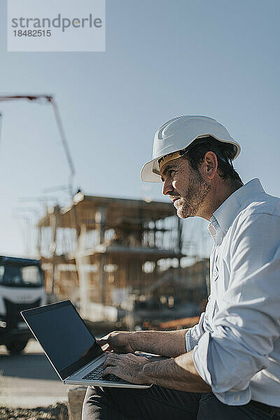 Nachdenklicher Architekt sitzt mit Laptop auf der Baustelle