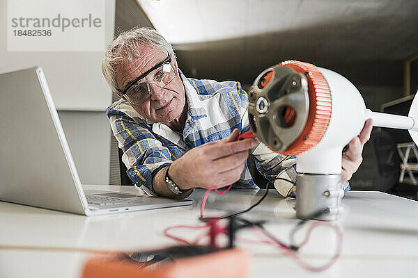 Techniker untersucht den Rotor einer Windkraftanlage auf dem Schreibtisch im Büro