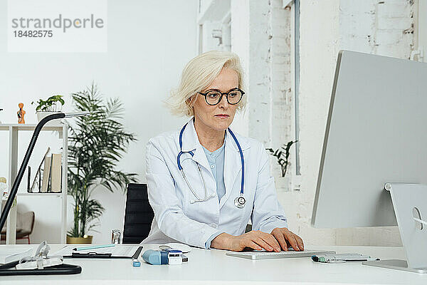 Reifer Arzt  der in der Klinik am Desktop-PC arbeitet