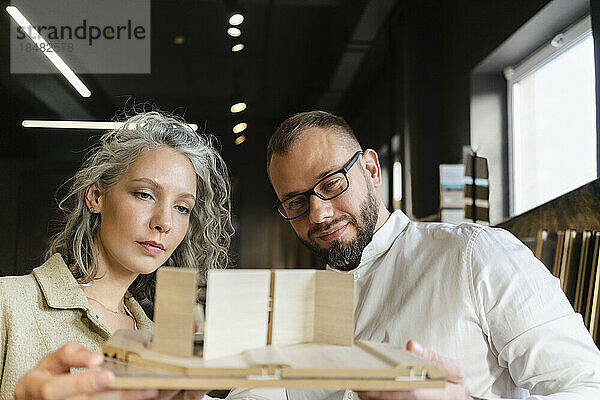 Two colleagues working on wooden model in architect's office together