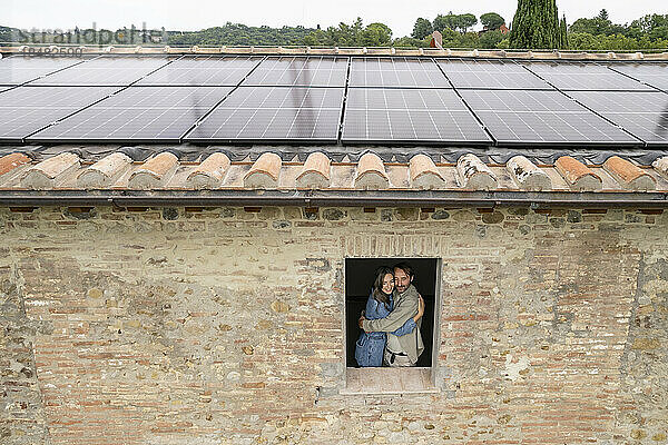 Glückliches älteres Paar  gesehen durch Fenster mit Sonnenkollektoren auf dem Dach