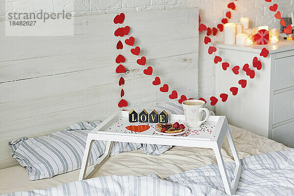 Frühstückstablett mit herzförmiger Dekoration im Schlafzimmer zu Hause