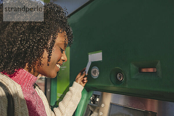 Lächelnde Frau mit Kreditkarte am Geldautomaten