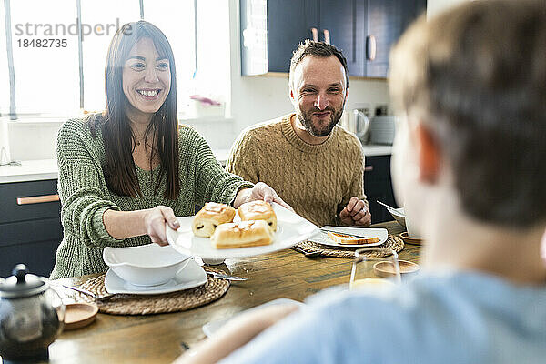 Glücklicher Vater und Mutter  die ihrem Sohn zu Hause Frühstück servieren