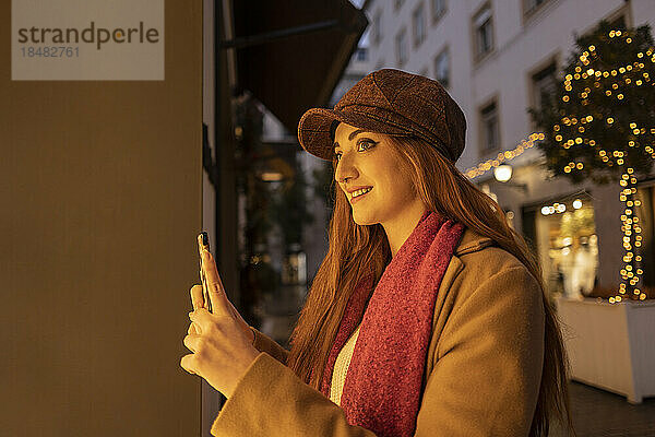 Glückliche Frau mit Mütze fotografiert per Smartphone