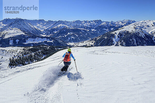 Österreich  Tirol  Skifahrerin rutscht den schneebedeckten Hang in den Kitzbüheler Alpen hinunter