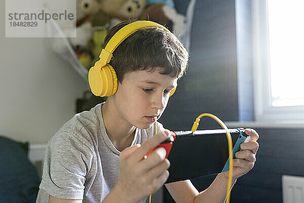 Junge trägt Kopfhörer und spielt zu Hause ein Videospiel auf einem Tablet-PC