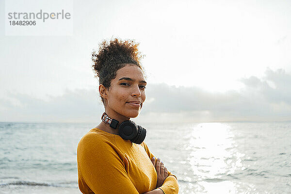 Junge Frau mit Kopfhörern vor dem Meer
