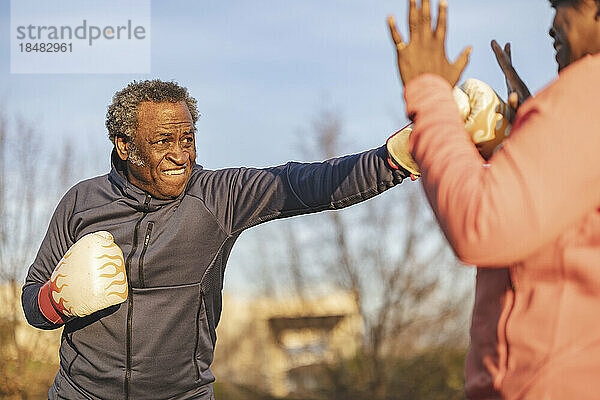 Älterer Mann übt Boxen mit Frau im Park