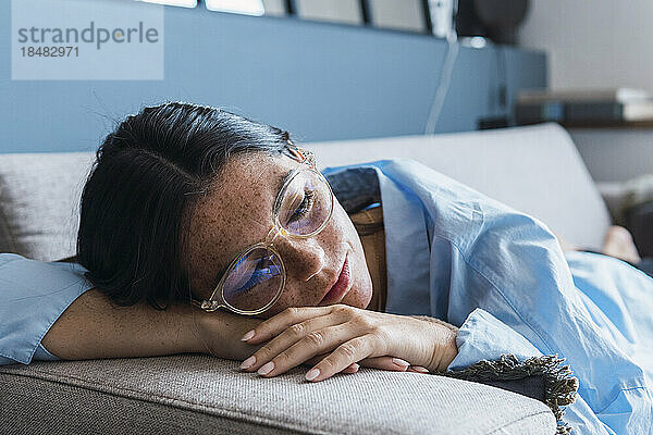 Thoughtful woman resting on sofa at home