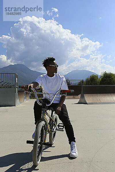 Junger Mann sitzt auf einem BMX-Fahrrad im Skatepark