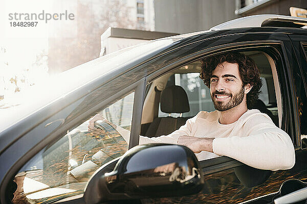 Happy young man driving car on sunny day