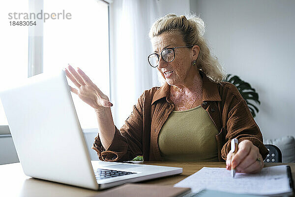 Geschäftsfrau spricht per Videoanruf über Laptop am Schreibtisch im Heimbüro