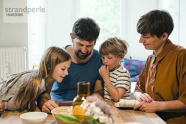 Familie schaut gemeinsam am Esstisch zu Hause auf den Tablet-PC