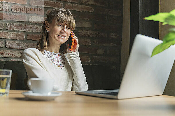 Freiberufler spricht im Café mit Smartphone