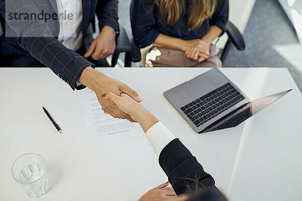 Recruiter shaking hand with candidate after successful interview at office