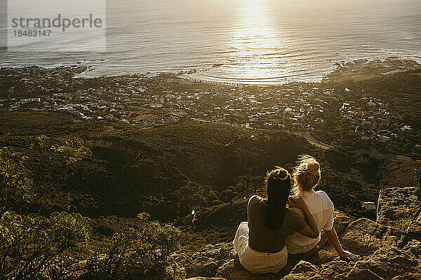 Freunde sitzen auf einem Felsen am Signal Hill und bewundern das Meer