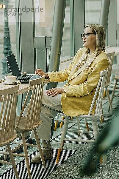 Nachdenkliche Geschäftsfrau sitzt auf einem Stuhl im Café