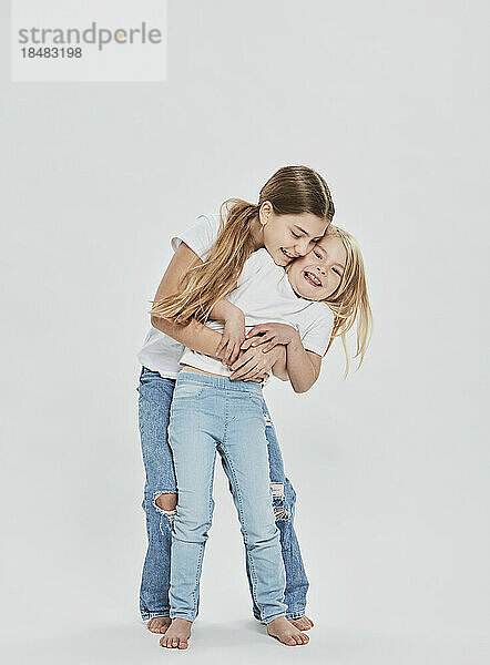 Happy sisters having fun against white background