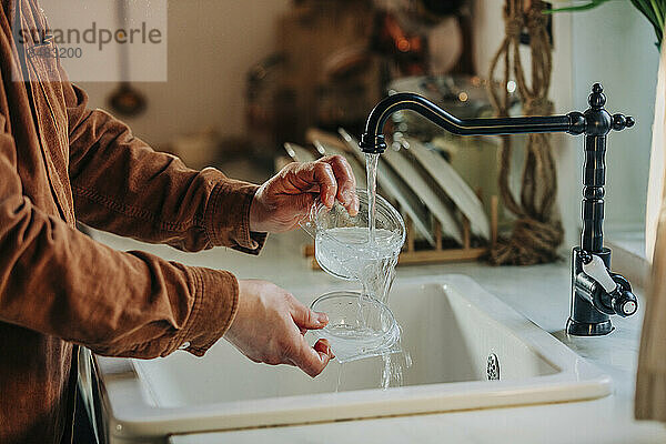Mann wäscht Plastikbehälter in der Küche zu Hause