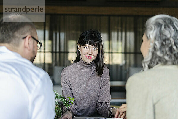 Smiling woman having a meeting with businessman and businesswoman in office