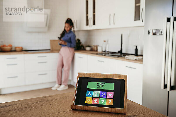 Hausautomations-App auf Tablet-PC mit Frau im Hintergrund