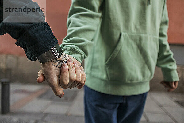 Schwules Paar hält Händchen auf Fußweg