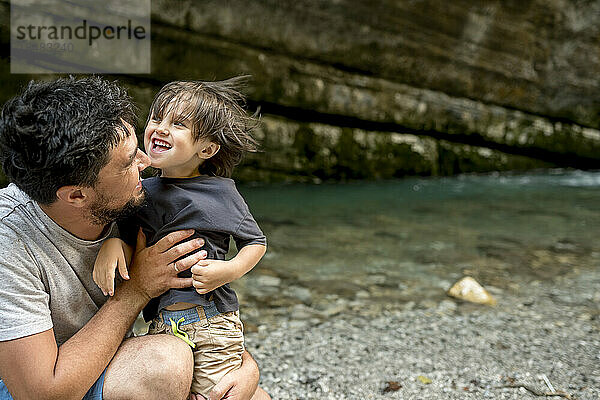 Glücklicher Vater spielt mit Sohn am Flussufer