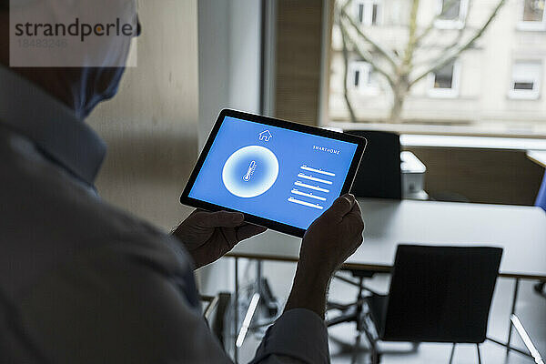 Geschäftsmann mit Tablet-PC zeigt im Büro die Anzeige der Hausautomations-App
