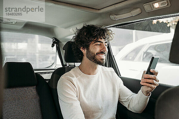 Glücklicher Mann benutzt Smartphone im Auto