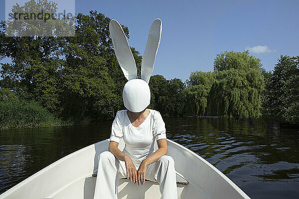 Woman wearing rabbit mask sitting in boat