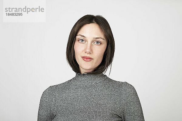 Confident young woman wearing turtleneck against white background