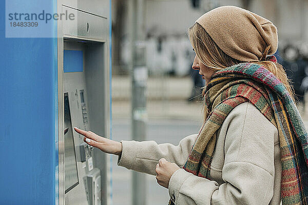 Junge Frau benutzt Fahrkartenautomaten