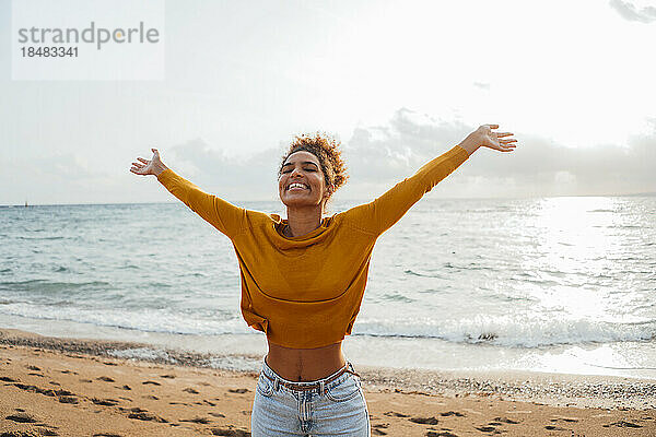 Happy woman with arms outstretched enjoying at beach