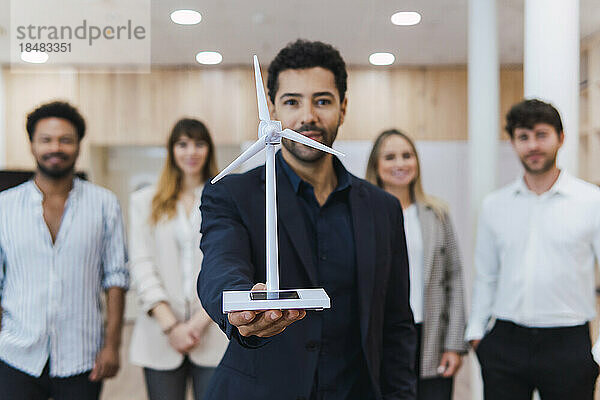 Geschäftsmann hält Windturbinenmodell vor seinem Team im Büro
