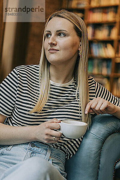 Nachdenkliche Frau sitzt mit Kaffeetasse im Café