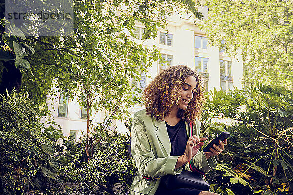 Geschäftsfrau benutzt Mobiltelefon im Park