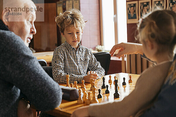 Kinder spielen Schach mit Großvater im Country Club