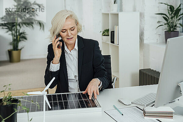Geschäftsfrau mit Solarpanel telefoniert am Schreibtisch