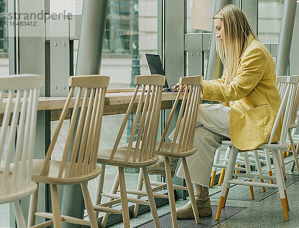 Geschäftsfrau sitzt mit Laptop auf Stuhl im Café