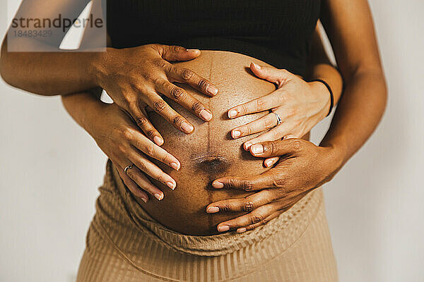 Hände von Frauen berühren schwangeren Bauch