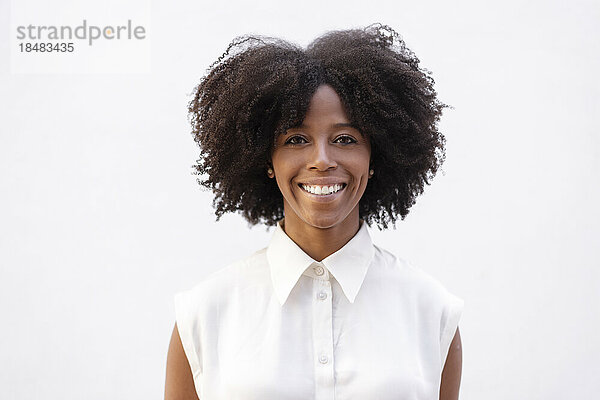 Glückliche junge Frau mit Afro-Frisur vor weißem Hintergrund