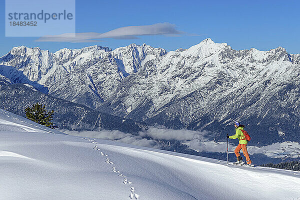 Österreich  Tirol  Skifahrerin steigt schneebedeckten Hang in den Tuxer Alpen hinauf