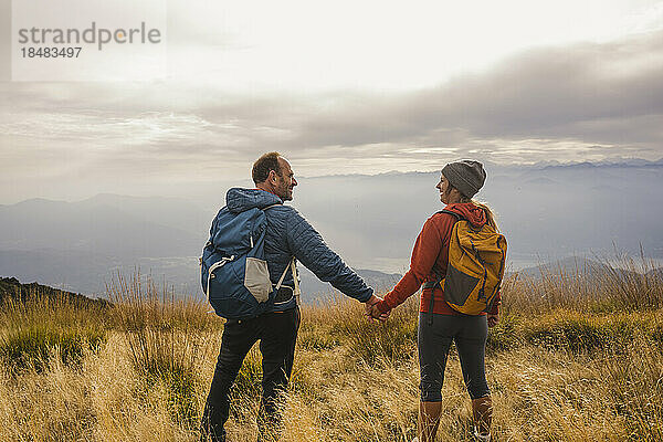 Glücklicher reifer Mann und Frau halten sich am Berg an den Händen
