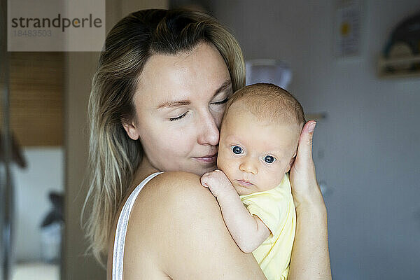 Mutter mit geschlossenen Augen trägt einen kleinen Jungen