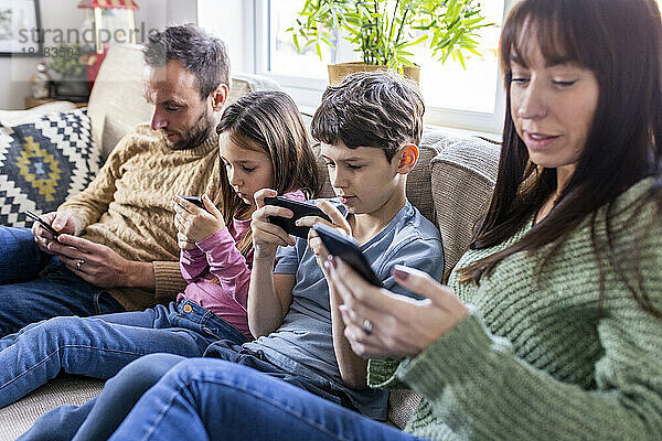 Familie benutzt Mobiltelefon zu Hause auf dem Sofa