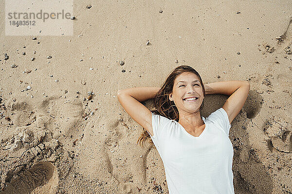 Happy woman lying on sand at beach