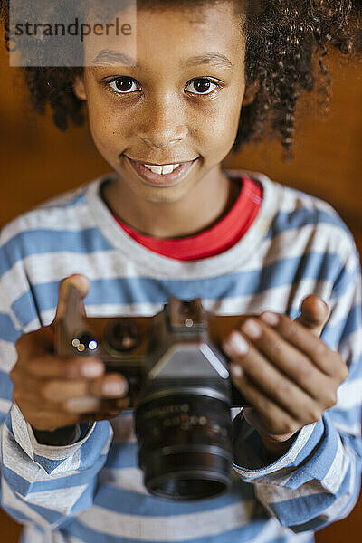 Smiling boy holding antique camera