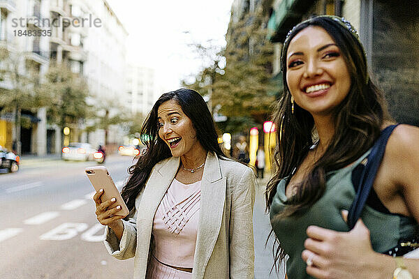 Überraschte Frau benutzt Smartphone mit Freund  der auf der Straße steht