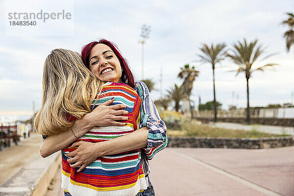 Glückliche Freunde  die sich an der Promenade umarmen